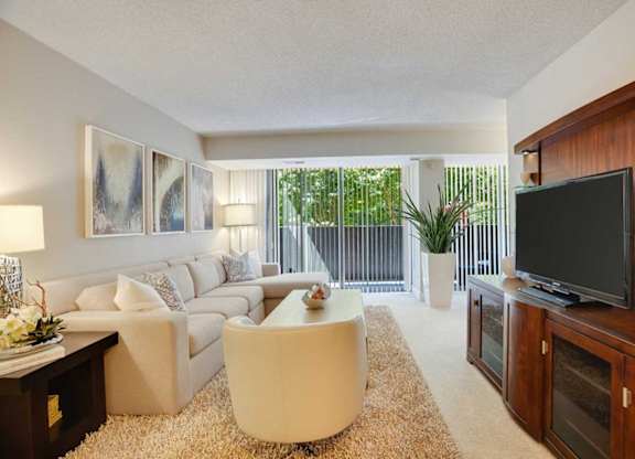 A living room with a white couch, a white coffee table, and a flat screen TV.