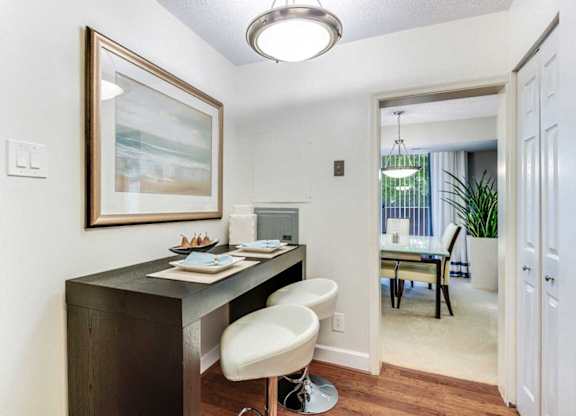 A home office with a desk, chair, and painting on the wall.