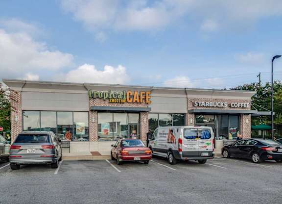 A Starbucks Coffee shop with a parking lot in front.