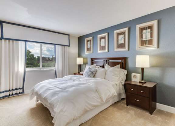 A bedroom with a large bed and a window with curtains.