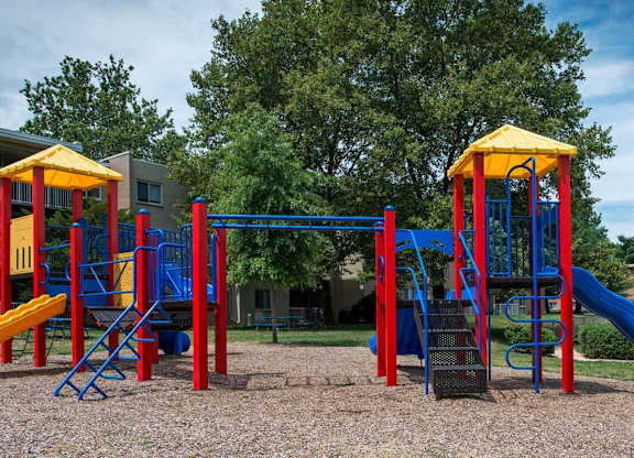 A playground with a blue and yellow slide and a red and yellow structure.