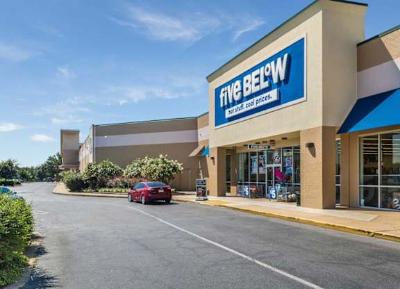 A Five Below store with a red car parked in front.