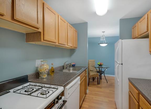 A kitchen with a white stove top oven and wooden cabinets.