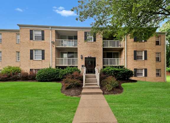 A brick apartment building with a green lawn in front.