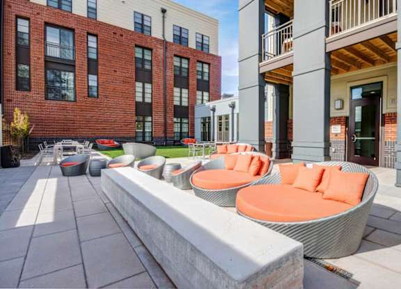 A modern outdoor seating area with orange chairs and a white bench.