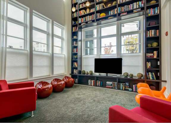 A living room with a large bookshelf filled with books and a flat screen TV.