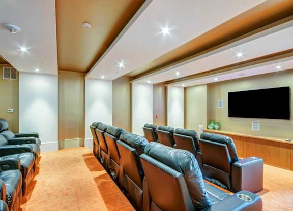 A movie theater with a row of seats and a large screen.