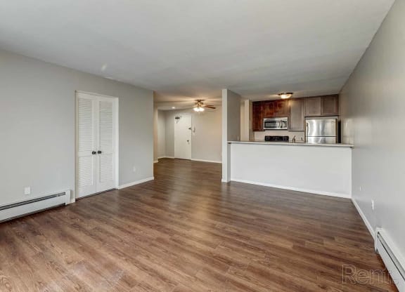 an empty living room and kitchen with wood flooring