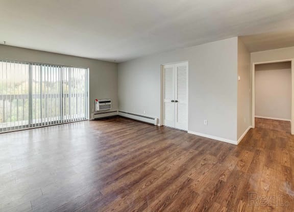 an empty living room with wood floors and a large window