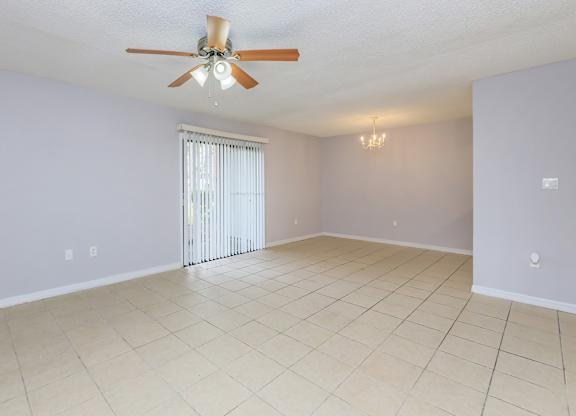 an empty living room with a ceiling fan and a tiled floor