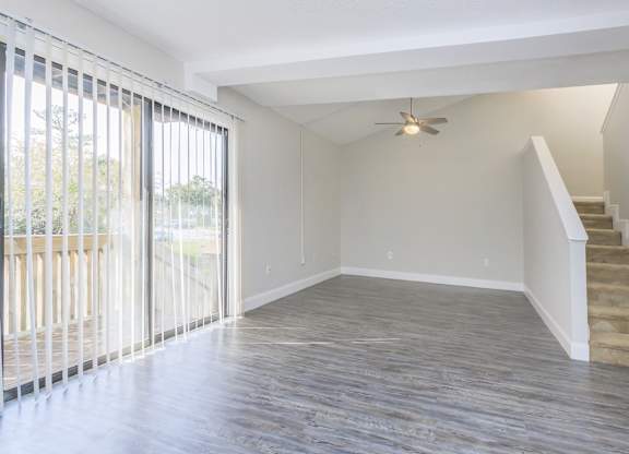 an empty living room with a staircase and a ceiling fan