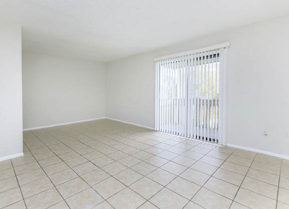 an empty living room with a sliding glass door and tiled floor