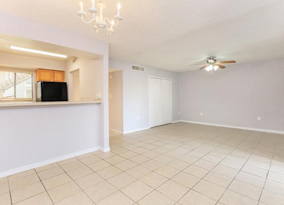 the living room and dining room of an empty home with a ceiling fan