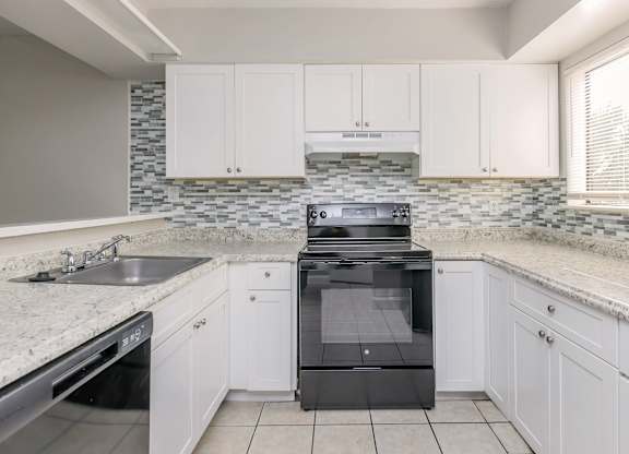 a kitchen with white cabinets and a stove and a sink
