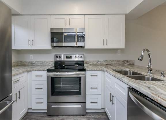 a kitchen with white cabinets and stainless steel appliances
