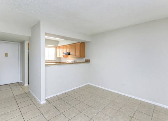 the living room and kitchen of an empty house with a tiled floor