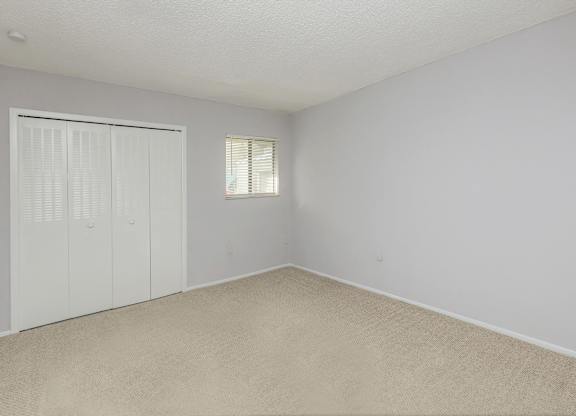 an empty bedroom with a closet and a window