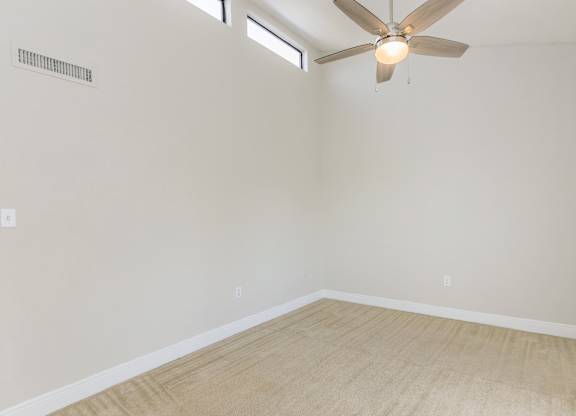 an empty room with a ceiling fan and white walls