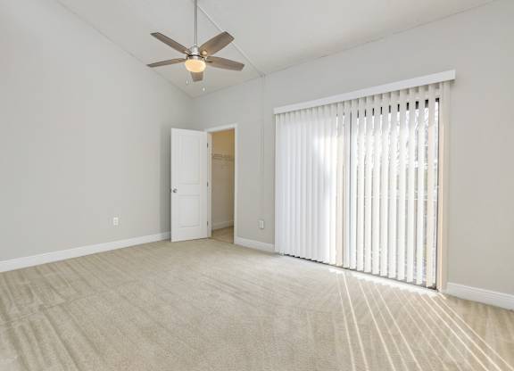 an empty living room with blinds and a ceiling fan