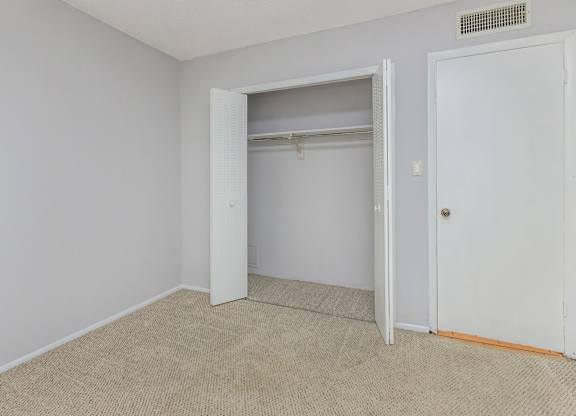 an empty bedroom with an open closet door