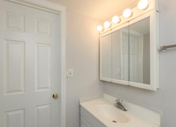 a bathroom with a sink and a mirror and a door