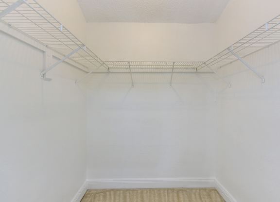 an empty white room with a wire rack on the wall