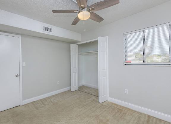 a bedroom with a ceiling fan and a door to a closet
