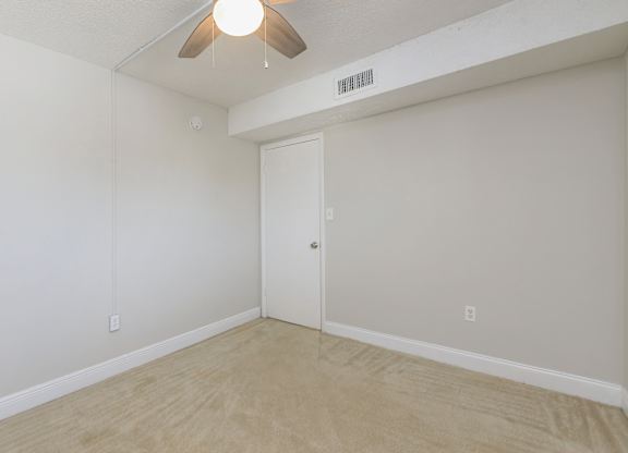 an empty room with a ceiling fan in the corner