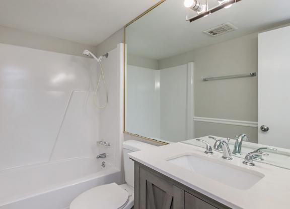 a bathroom with a sink toilet and shower and a mirror