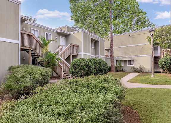 a group of apartments with stairs and grass and trees