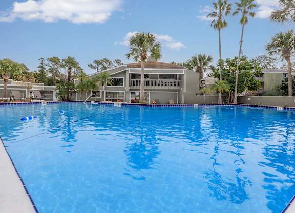 a large pool in front of a building with palm trees