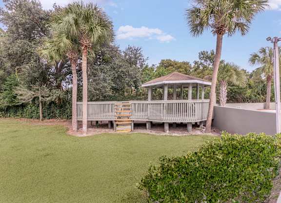 a gazebo in the backyard of a home with palm trees