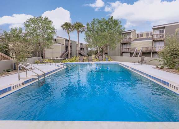 a large swimming pool with apartments in the background