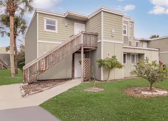 a yellow house with a wooden deck and a sidewalk