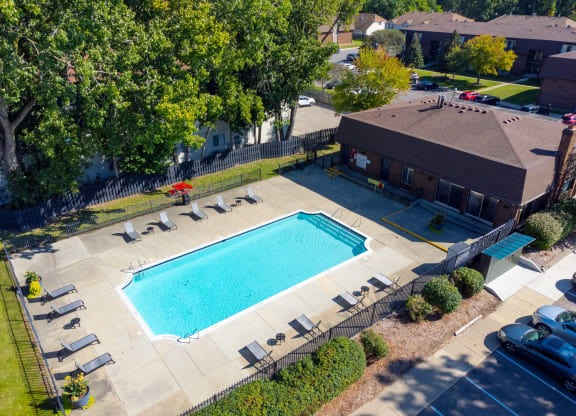 Large open area with heated pool and lounge chairs at Knottingham Apartments in Clinton Township, MI