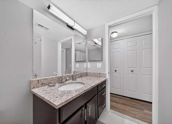 Modern bathroom with large vanity mirror and tub/shower at Lakeside Village Apartments in Clinton Township, MI