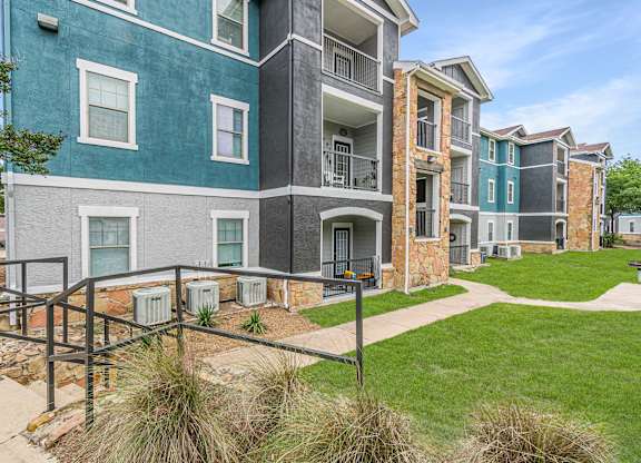 A multi-story apartment building with a green lawn in front.