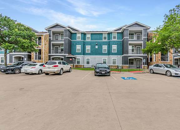 A parking lot in front of a multi-story apartment building.