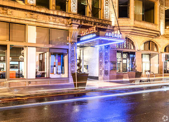 A wet street in front of a building with an illuminated sign that says "Arcade".