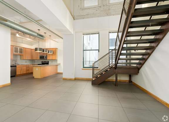 A spacious kitchen with a staircase leading to the upper floor.