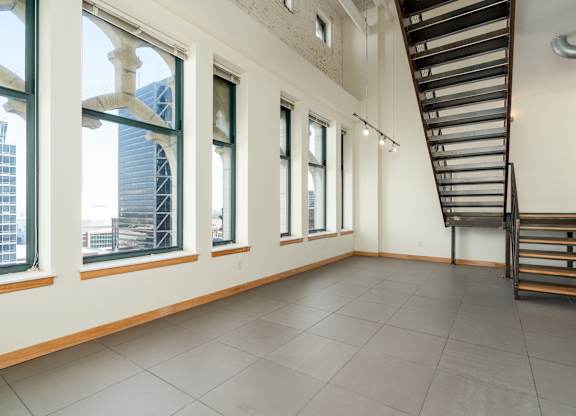 A room with a staircase and large windows overlooking a cityscape.