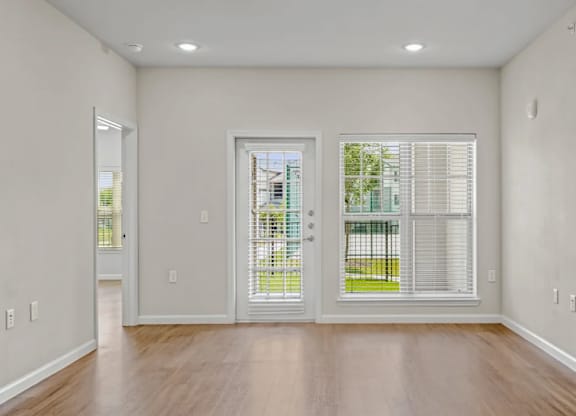 an empty living room with windows and wood floors at Cypress Creek at River Oaks, Texas, 75165