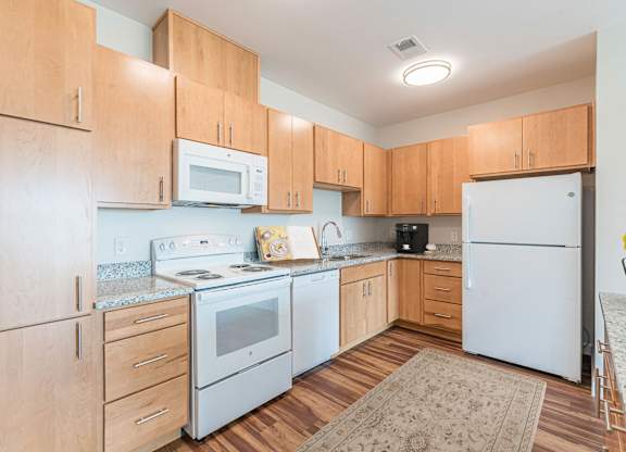 A kitchen with wooden cabinets and white appliances. at Avery Landing Apartments, Greenville, South Carolina