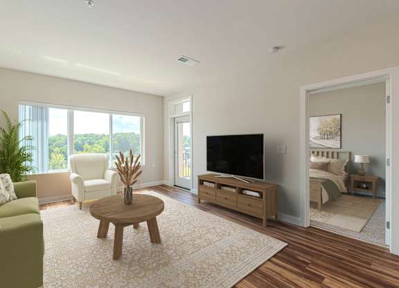 A living room with a green couch, a wooden coffee table, and a flat screen TV. at Avery Landing Apartments, South Carolina