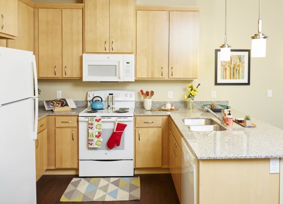  a kitchen with wooden cabinets and a granite countertop at The Cambric Senior Apartments, St. Paul, 55106