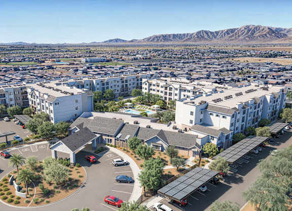 A large white building with a parking lot in front of it at Orchard Springs 55+ Apartment , Arizona