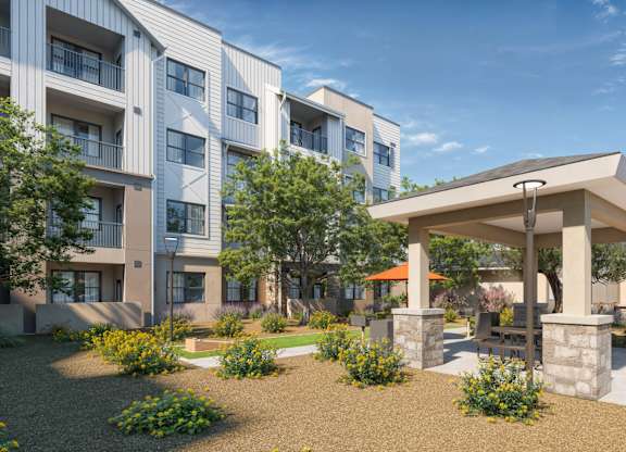 A modern apartment complex with a gazebo-like structure in the front yard at Orchard Springs 55+ Apartment , Surprise