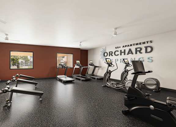 A gym room with a variety of equipment including treadmills, stationary bikes, and weight machines at Orchard Springs 55+ Apartment , Surprise, Arizona