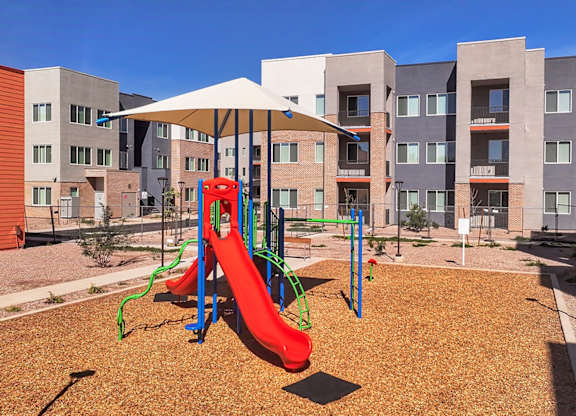 A playground with a red slide and a white canopy.