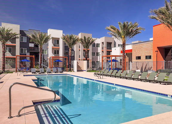A swimming pool in front of a building with palm trees.